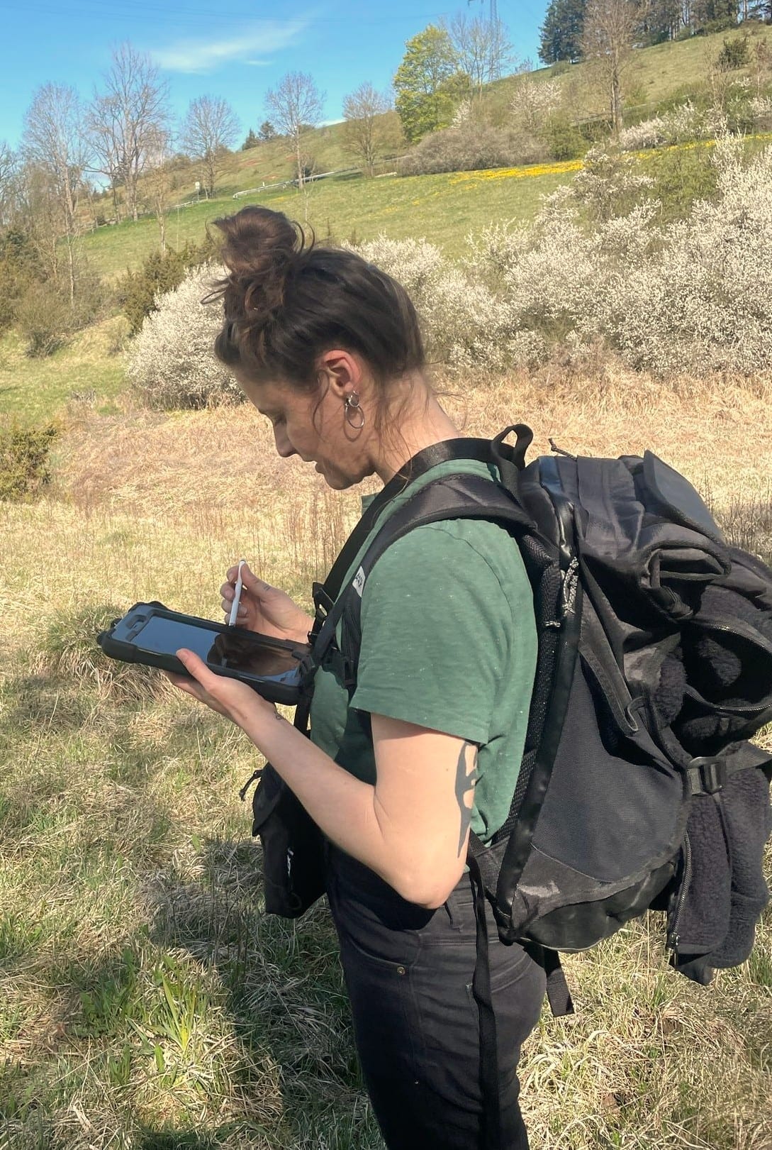 Heidi Mühl mit Fernglas bei der Brutvogelkartierung im Gelände in Baden-Württemberg